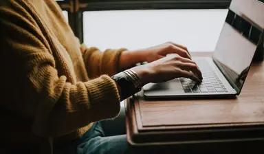 Hands typing an application on a laptop