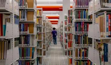 A student walking between library shelves